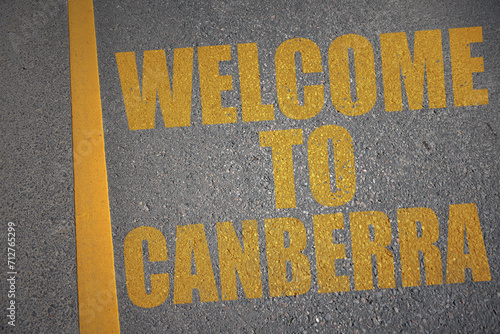 asphalt road with text welcome to Canberra near yellow line.