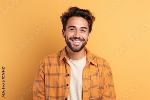 Portrait of a handsome young man smiling at camera over yellow background © Inigo