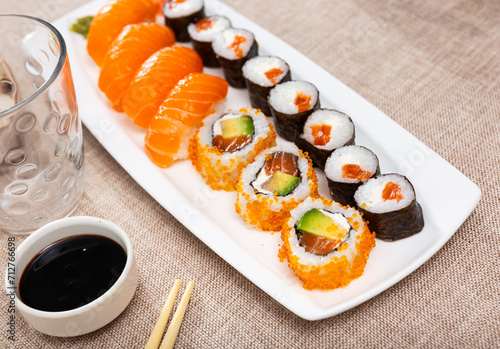 Roll maki and urumaki with salmon and nigiri sushi served with bowl of soy sauce