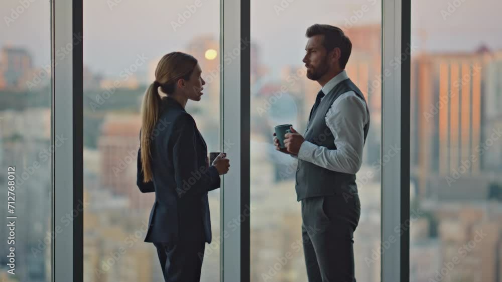 Evening partners discussing project admiring cityscape at panoramic workplace. Evening partners discussing project admiring cityscape at panoramic workplace.