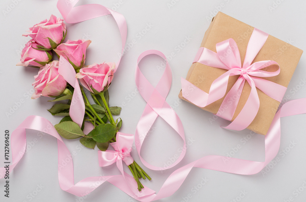 Composition with pink roses, gift box and eight made of ribbon on color background, top view. Women's day concept