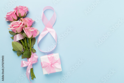 Composition with pink roses, gift box and eight made of ribbon on color background, top view. Women's day concept