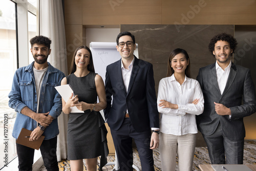 Multiethnic team of cheerful successful young managers smiling at camera, standing in line for group business professional portrait together, promoting teamwork, collaboration spirit