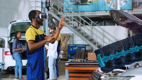 Technician in repair shop using advanced virtual reality technology to visualize car engine turbine in order to fix it. Experienced garage expert wearing vr glasses while repairing defective vehicle
