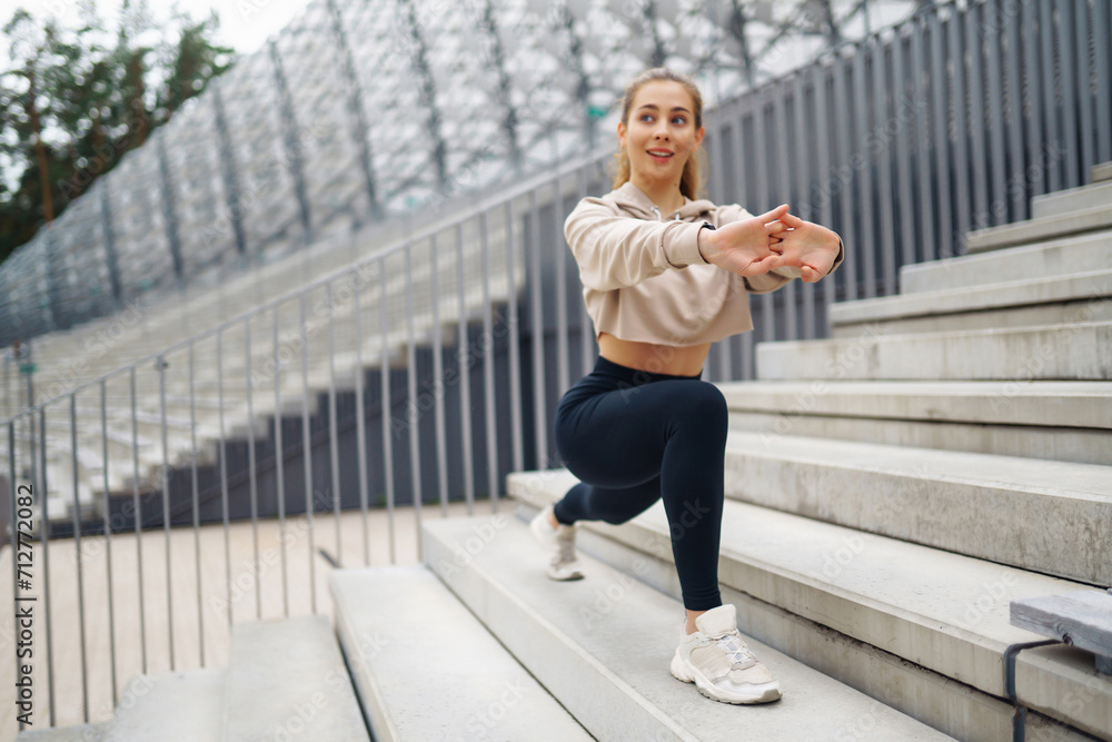 Happy woman in sports outfit doing exercises outdoors in the morning. Sport woman doing stretching exercise. Sport, Active life, sports training, healthy lifestyle.