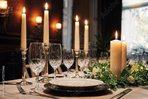 A table set with plates, wine glasses, and candles.