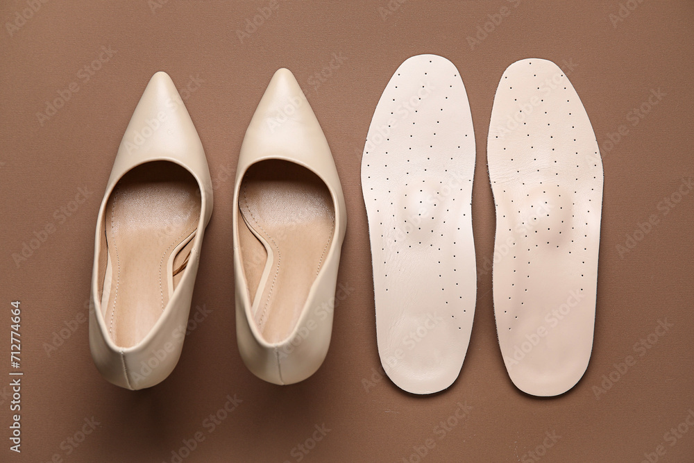 Pair of orthopedic insoles and high heeled shoes on color background Pair of orthopedic insoles and high heeled shoes on color background