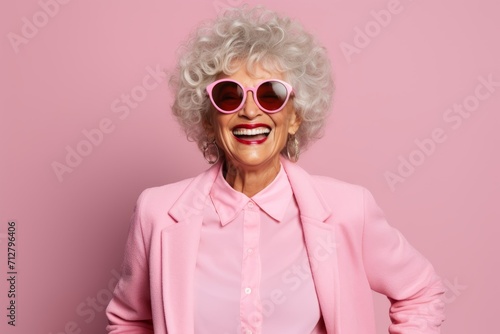Portrait of happy senior woman in sunglasses. Isolated on pink background. © Iigo