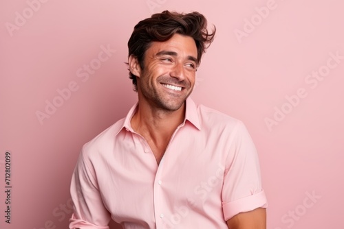 Portrait of a handsome smiling young man in pink shirt against pink background