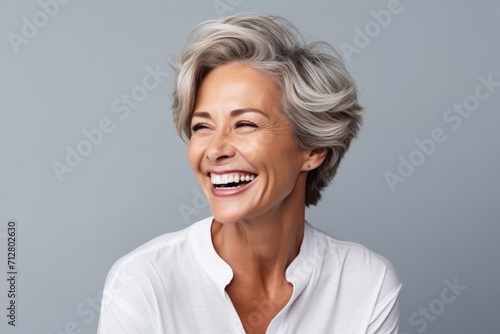 portrait of happy senior woman with grey hair laughing over grey background