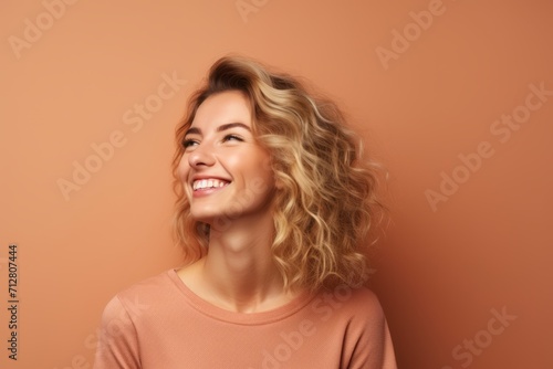 Cheerful young woman with long wavy hair on orange background