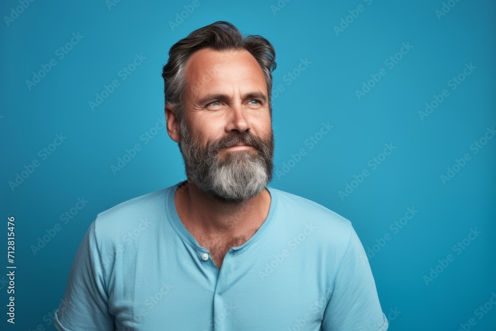 Portrait of a handsome mature man with gray beard and mustache looking at camera over blue background Portrait of a handsome mature man with gray beard and mustache looking at camera over blue background