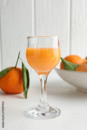 Tasty tangerine liqueur in glass and fresh fruits on white table