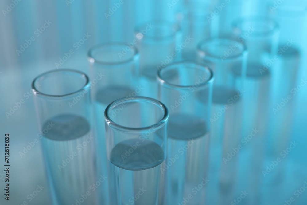Laboratory analysis. Many glass test tubes on light blue background, closeup Laboratory analysis. Many glass test tubes on light blue background, closeup