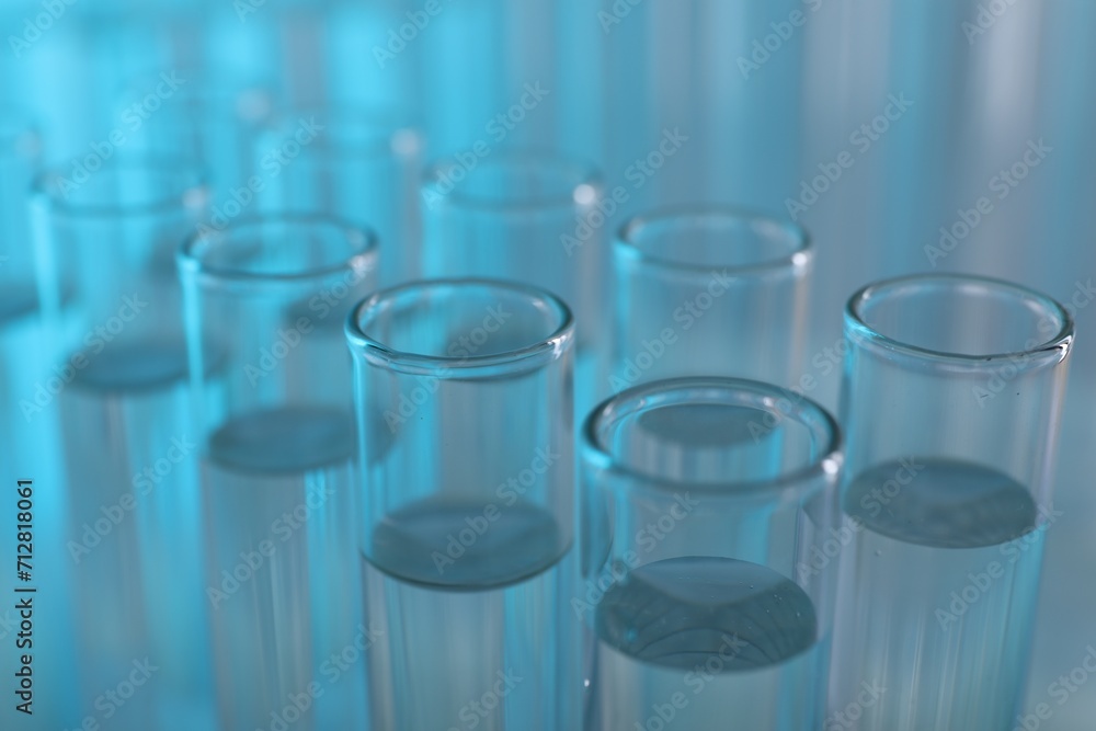 Laboratory analysis. Many glass test tubes on light blue background, closeup Laboratory analysis. Many glass test tubes on light blue background, closeup