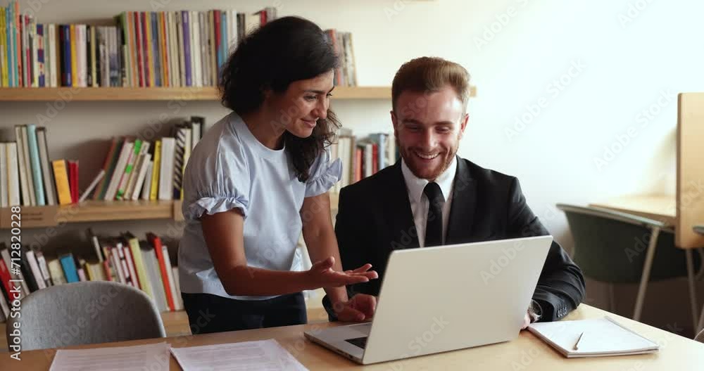 Friendly Indian office employee helps with online task, corporate program, new software to young Caucasian male colleague showing to workmate solution, engaged in teamwork at workplace. Apprenticeship Friendly Indian office employee helps with online task, corporate program, new software to young Caucasian male colleague showing to workmate solution, engaged in teamwork at workplace. Apprenticeship