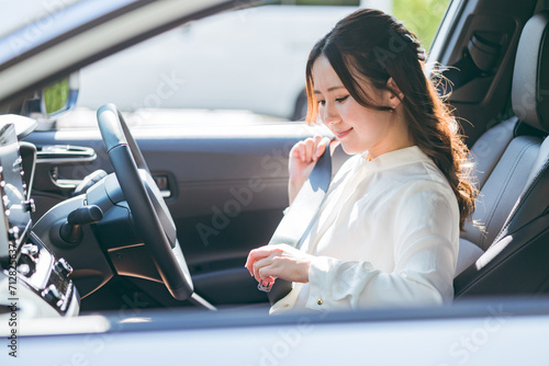 車に乗り込みシートベルトをする女性ドライバー（交通ルール・安全運転・交通安全）
 photo
