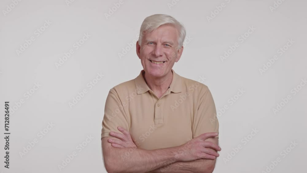 gray haired man looking at camera and crossing arms over his chest. studio shot gray haired man looking at camera and crossing arms over his chest. studio shot