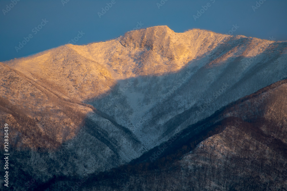 朝の太陽に照らされた雪山。