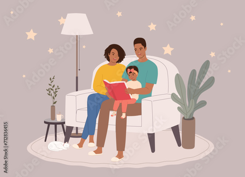 Smiling Black Parents Sitting On Couch Reading A Bedtime Story Together With Their Little Daughter During Night Time. Full Length.