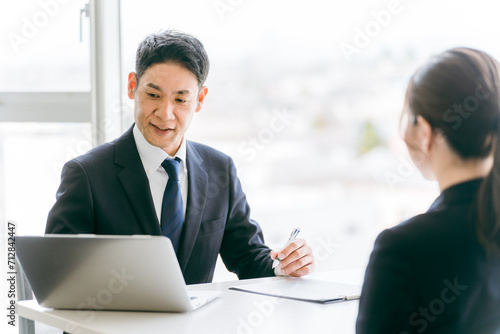 Cuadro en lienzo パソコンを使って説明・相談・案内するスーツ姿のビジネスマンと話を聞く女性