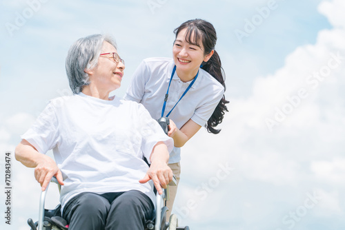 青空と介護福祉士・介護士と高齢者・シニア女性・おばあちゃん
 photo