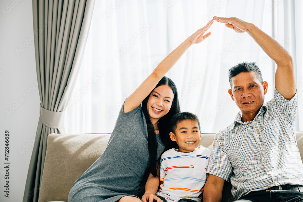 A happy family of four on a sofa parents gesturing a roof above their little son. Depicting concepts of house insurance children protection and future planning ensuring family safety and unity. A happy family of four on a sofa parents gesturing a roof above their little son. Depicting concepts of house insurance children protection and future planning ensuring family safety and unity.