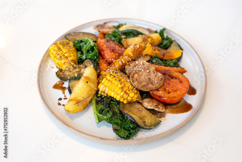 Selective focus. Grilled vegetables with herbs and Mexican sauce in a white circle dish on the white stone table.
