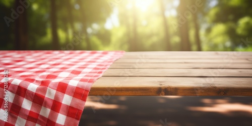 Picnic table with a red checkered towel, empty space, and a blurred wooden deck backdrop. Promotion display. photo