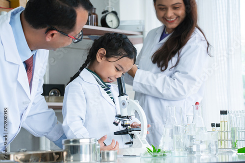 Asian scientist kid student and Indian teacher with plant at biology class in school laboratory  smiling  teaching child girl to use microscope. Education  science and school concept