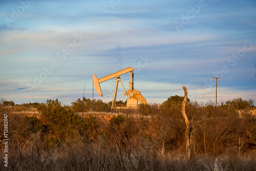 Solo pumpjack on the edge of West Texas lake bathed in late afternoon sunlight.