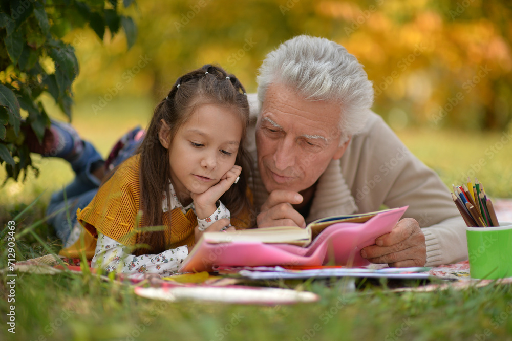 girl and grandfather doing homework in autumn park girl and grandfather doing homework in autumn park