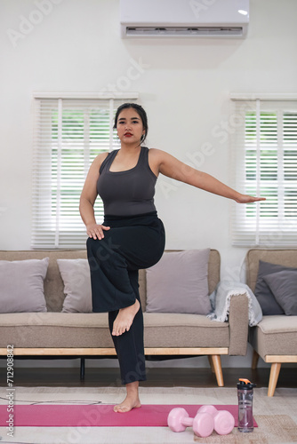 Overweight Asian woman exercising at home on a fitness mat. Beautiful Caucasian woman in casual clothes Preparing to do yoga Practice exercise in the living room © chartchai