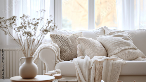 Scandinavian, hygge home interior design of modern living room. Cozy white sofa with pillows and blanket against window 