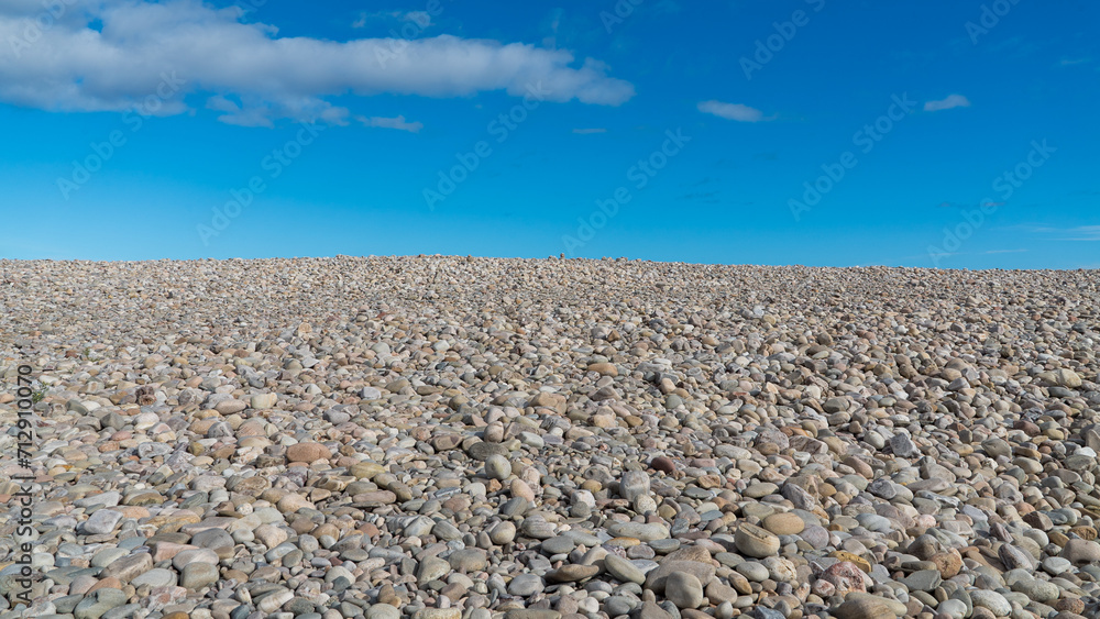 Pebbles on the beach with blue sky and light clouds on the coast of Scotland Pebbles on the beach with blue sky and light clouds on the coast of Scotland