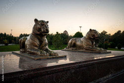 Statues of tigers against the background of evening sky. Shot in the park of Amir Timur, Samarkand, Uzbekistan photo