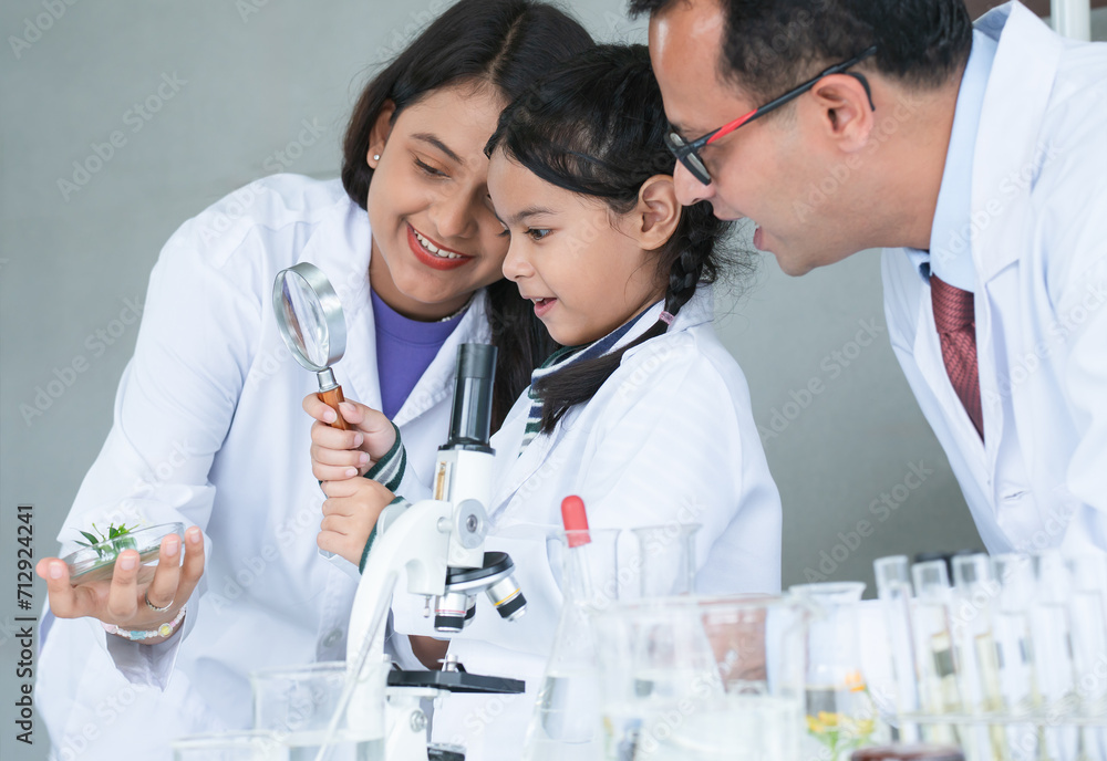 Asian scientist kid student and Indian teacher have fun with plant at biology class in school laboratory, do an experiment, using magnifying glass and microscope. Education, science and school concept Asian scientist kid student and Indian teacher have fun with plant at biology class in school laboratory, do an experiment, using magnifying glass and microscope. Education, science and school concept