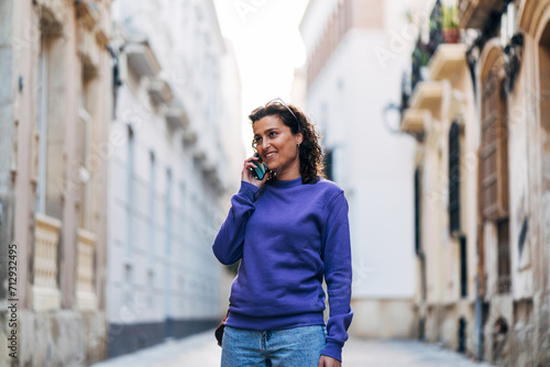 Positive woman talking on smartphone in city