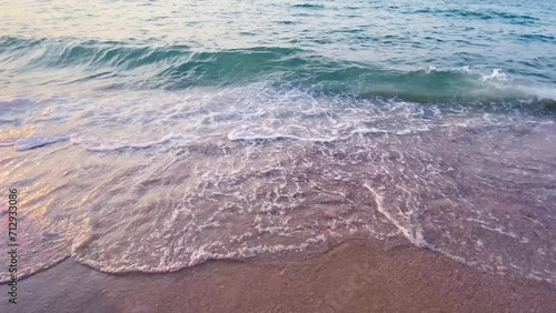Beach waves gently roll along the sandy shore, beneath a sky painted with clouds, capturing the serene beauty of a summer seascape