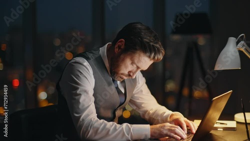 Busy employee working dark office at night. Focused boss typing computer online photo