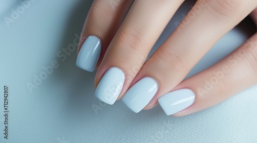 Stylish pale blue manicured nails on a female hand.