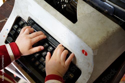 Little boy’s hand typing on a vintage mechanical typewriter machine