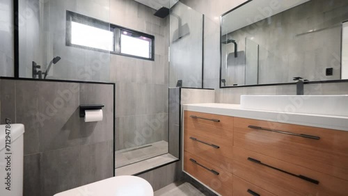 Executive double shower with modern wooden cabinetry grey floor to ceiling tiles and full length mirror restroom interior. photo