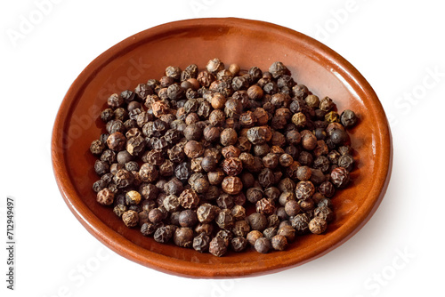 Plate with black peppercorns. Peppercorns on a white background. Allspice peas close-up.