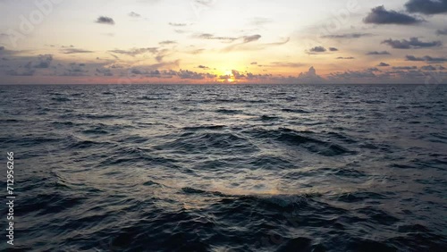 Flying over the ocean waves during sunset as the sun disappears into night. bird eye view 4K cinematic drone footage.