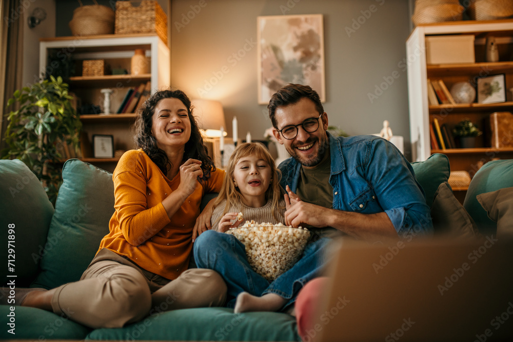 A family of three having a delightful time watching a film and snacking on popcorn A family of three having a delightful time watching a film and snacking on popcorn