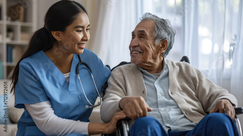 Caring female nurse in blue scrubs smiling and holding hands with an elderly male patient photo
