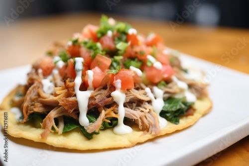 close-up of carnitas on a tostada with sour cream drizzle