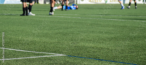selective focus, view of a soccer field during a match with a player lying on the ground out of focus in the background. sports medicine