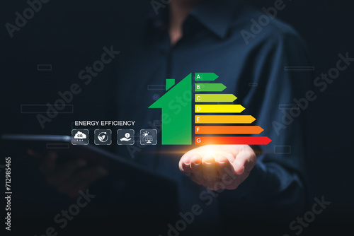 Energy efficiency concept. Businessman use tablet with virtual screen of energy efficiency rating for energy efficient house building rate label audit.